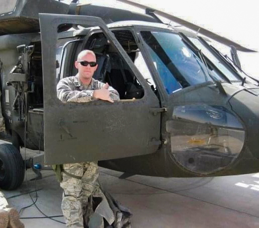 Then-Captain D. Blake Williams posing in uniform next to a military helicopter.